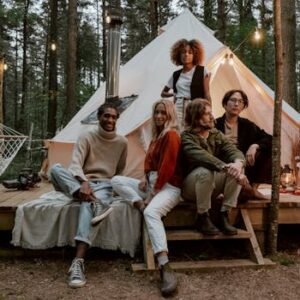 Friends gather for a relaxing glamping trip, embracing the comfort of nature in a forest setting.