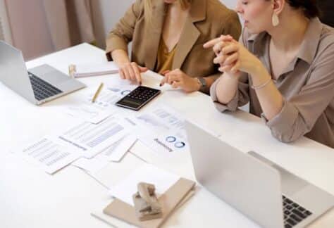 Two professionals collaborating on financial documents in a modern office setting.