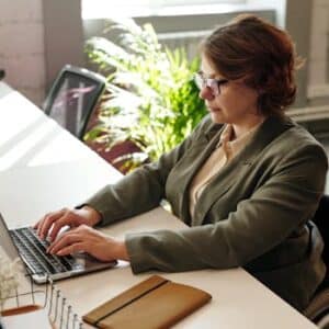 Businesswoman in wheelchair using laptop at office desk.