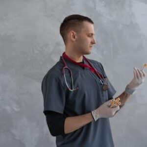A male doctor in scrubs and gloves analyzing a specimen with focus indoors.