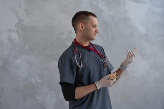 A male doctor in scrubs and gloves analyzing a specimen with focus indoors.