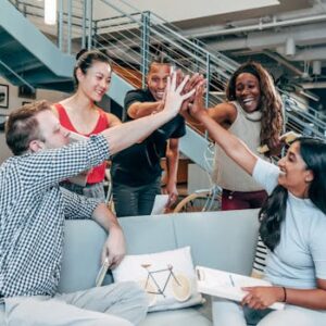 A multicultural office team high-fiving and celebrating a successful collaboration.