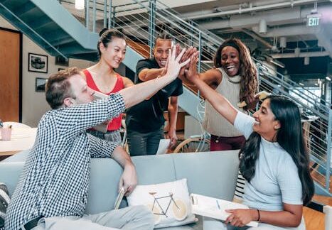 A multicultural office team high-fiving and celebrating a successful collaboration.