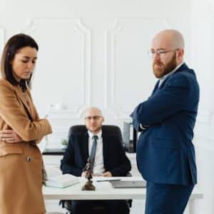 A couple in corporate attire seeks mediation during a business disagreement in an office setting.