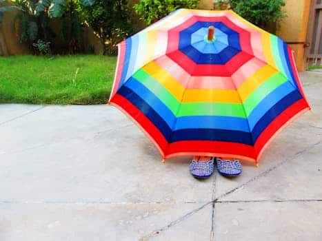 Bright and colorful rainbow umbrella shading patterned shoes on a sunny day.