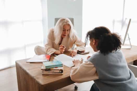 A tutor and student engaged in a learning session with books and notes on a table.