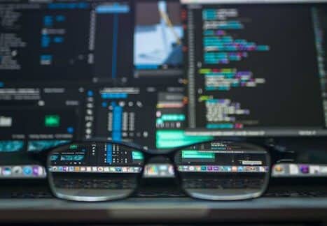 Eyeglasses reflecting computer code on a monitor, ideal for technology and programming themes.