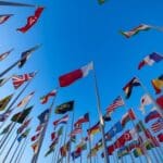 International flags waving against a clear blue sky in Doha, Qatar, symbolizing unity and diversity.