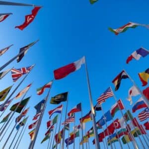 International flags waving against a clear blue sky in Doha, Qatar, symbolizing unity and diversity.