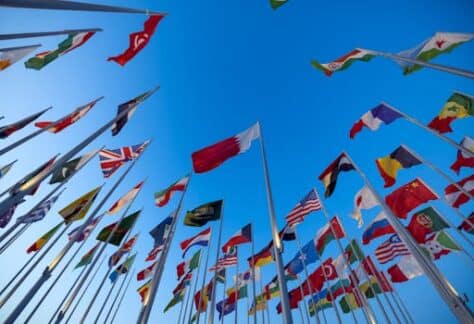 International flags waving against a clear blue sky in Doha, Qatar, symbolizing unity and diversity.