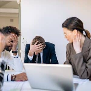 A group of stressed business professionals in an office setting, overwhelmed by work.