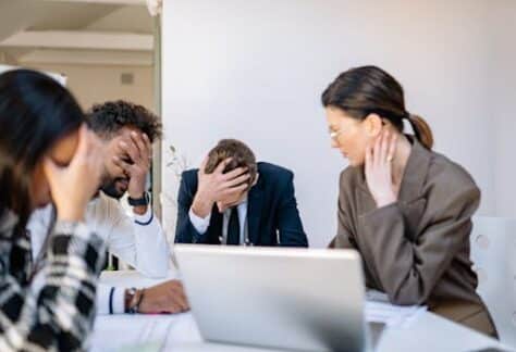 A group of stressed business professionals in an office setting, overwhelmed by work.