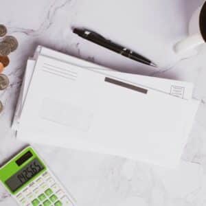 Flat lay of financial documents, calculator, coins, and coffee cup on marble surface.